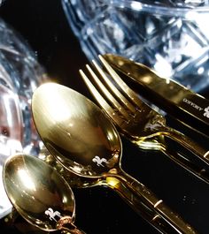 gold colored utensils and spoons sitting on top of each other in front of clear glass containers