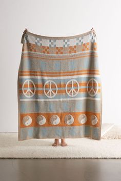 an orange and blue towel with peace signs on it sitting on a white rug in front of a wall