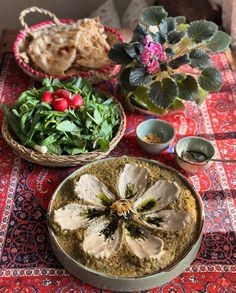 a table topped with bowls filled with food next to a basket full of vegetables and bread