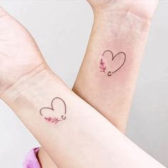 two matching wrist tattoos with hearts and flowers on each one arm, both in black ink