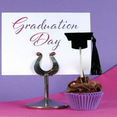 a cupcake with a graduation cap on it next to a sign that says graduation day