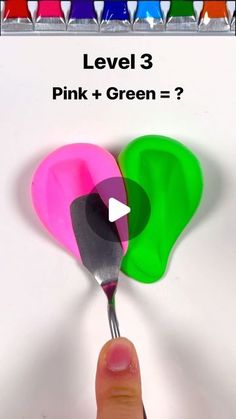 a hand holding a spoon with pink and green heart shaped utensils in it