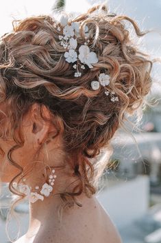 a woman with curly hair and flowers in her hair is looking off into the distance