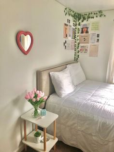 a bed with white sheets and pink flowers in a small room next to a window