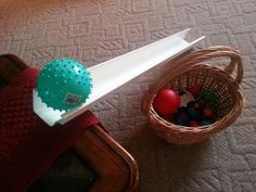 a basket filled with balls sitting on top of a bed next to a wooden table