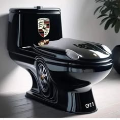 a black toilet sitting on top of a wooden floor next to a potted plant