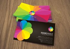 two colorful business cards sitting on top of a wooden table