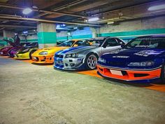 five different colored cars are lined up in a parking garage