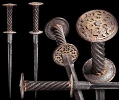 an assortment of metal objects on display against a black background, including two swords and four other items