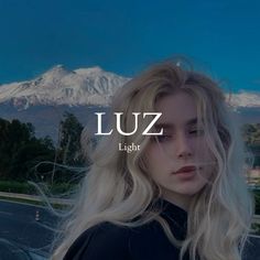 a woman with long blonde hair standing in front of a mountain and the words luz light above her