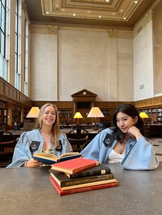 two women sitting at a table with books