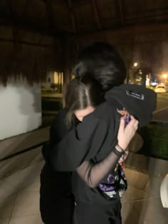 a woman holding a child in her arms while standing next to a building at night