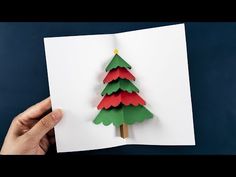 a hand holding up a folded paper christmas tree