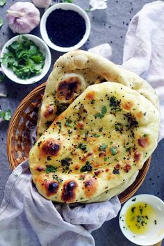 two pita breads sitting on top of a basket next to some dipping sauce