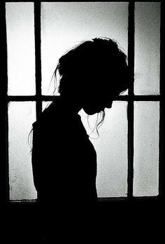 the silhouette of a woman standing in front of a window