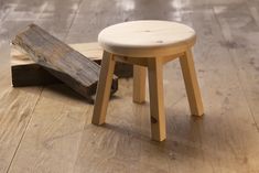 a small stool sitting on top of a wooden floor next to a piece of wood