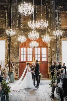 a bride and groom are standing in front of the chandelier at their wedding ceremony