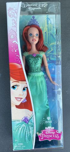 the little mermaid doll is in its box with her tiara and green dress on