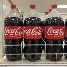 three bottles of coca - cola are sitting on the shelf