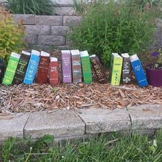 a row of books sitting on top of a pile of leaves next to a flower bed