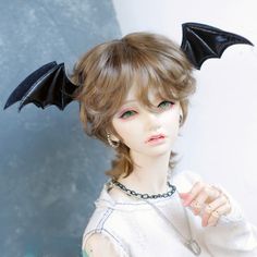 a doll is dressed up as a bat with horns on her head and hands in the air