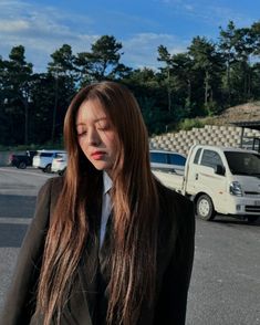 a woman with long hair standing in the middle of a parking lot