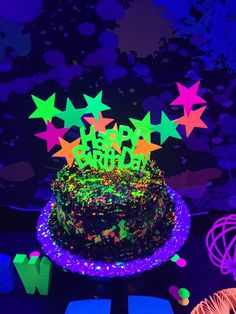 a birthday cake with stars on it and the words happy birthday written in neon lights