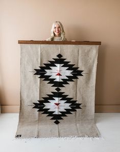 a woman standing behind a large black and white blanket with an arrow design on it