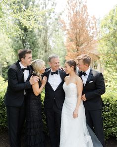 a group of people standing next to each other wearing tuxedos and bow ties