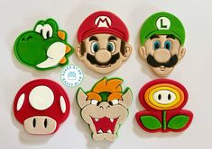 some mario bros cookies are arranged on a table with the faces of luigi, yoshi, and toad