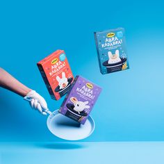 two boxes of milk being held up by someone's hand with white gloves on