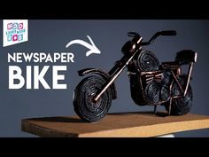 a miniature motorcycle is on top of a wooden shelf with the words news paper bike above it