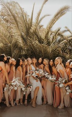 a group of women standing next to each other in front of palm trees and flowers