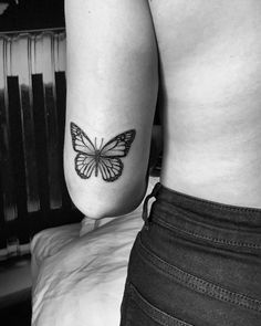 a black and white photo of a butterfly on the back of a woman's left arm