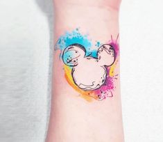 a wrist tattoo with a mickey mouse design on it's left arm and colorful ink splots