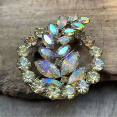 a brooch that is sitting on top of a piece of wood with lots of stones