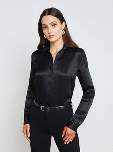 A quintessential blouse in a lustrous silk charmeuse and true black hue. Classic look has a soft, liquid hand and tailored silhouette shaped by sharp sartorial details like a stand collar, long button-cuff sleeves, and back yoke with inverted pleat. An open neckline and curved hem add subtle femininity. A nimble style that works equally well with jeans or skirts. Fastens in front with tonal buttons. | L'AGENCE Tyler Silk Blouse Top In Black Collarless Leather Jacket, Satin Blouses, Denim Blouse, Silk Charmeuse, A Stand, Cuff Sleeves, Blouse Top, Black Blouse, Silk Blouse