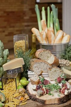 bread, cheese and other food items on a wooden table in front of some wine bottles