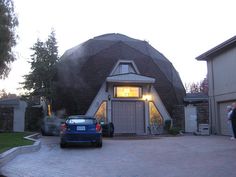 a car is parked in front of a house with a large dome on it's roof