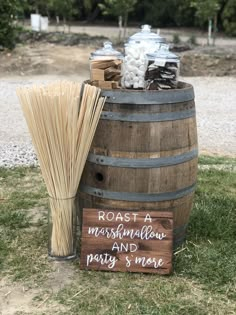 a wooden barrel sitting on top of a lush green field next to a sign that says roast marshmallow and party s'more