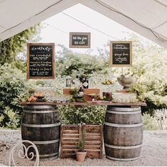 an outdoor bar with wine barrels and chalkboard signs