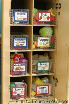 a wooden cabinet filled with lots of food and labeled labels on the doors to help kids learn how to eat