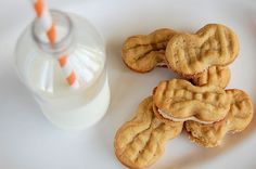 cookies and milk on a white plate next to a glass of orange striped straws