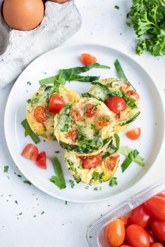 an egg muffin with tomatoes and green beans on a white plate next to some eggs