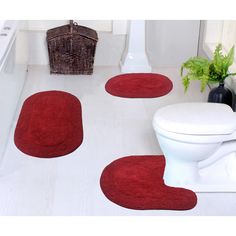 three red rugs on the floor next to a toilet