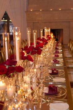 a long table is set with candles and red roses on it for a formal function