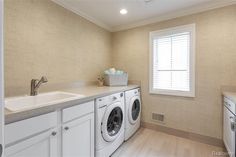 a washer and dryer in a very clean room with white cabinets, counter tops and drawers