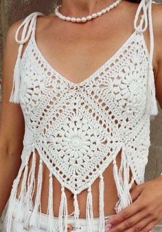 a woman wearing a white crochet top with tassels