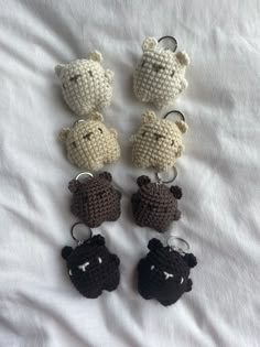 four crocheted keychains are arranged in the shape of bears on a white sheet