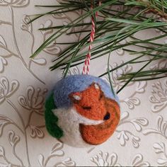 an ornament hanging from a tree branch with a red fox on it's head